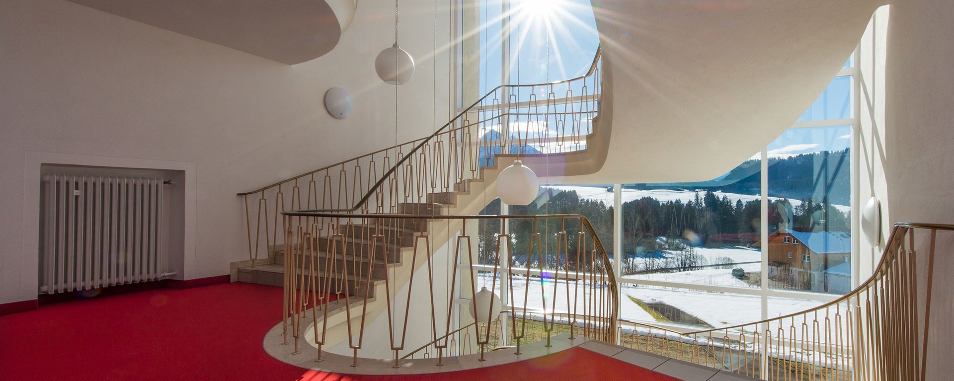 Treppenhaus der Suchtklinik - die Winterlandschaft bei Sonnenschein durch große Fenster gesehen