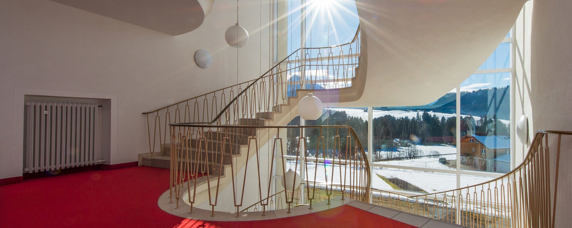Treppenhaus der Suchtklinik - die Winterlandschaft bei Sonnenschein durch große Fenster gesehen
